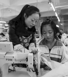 大英縣中等職業技術學校內，企業服裝技師正指導學生進行縫紉操作。